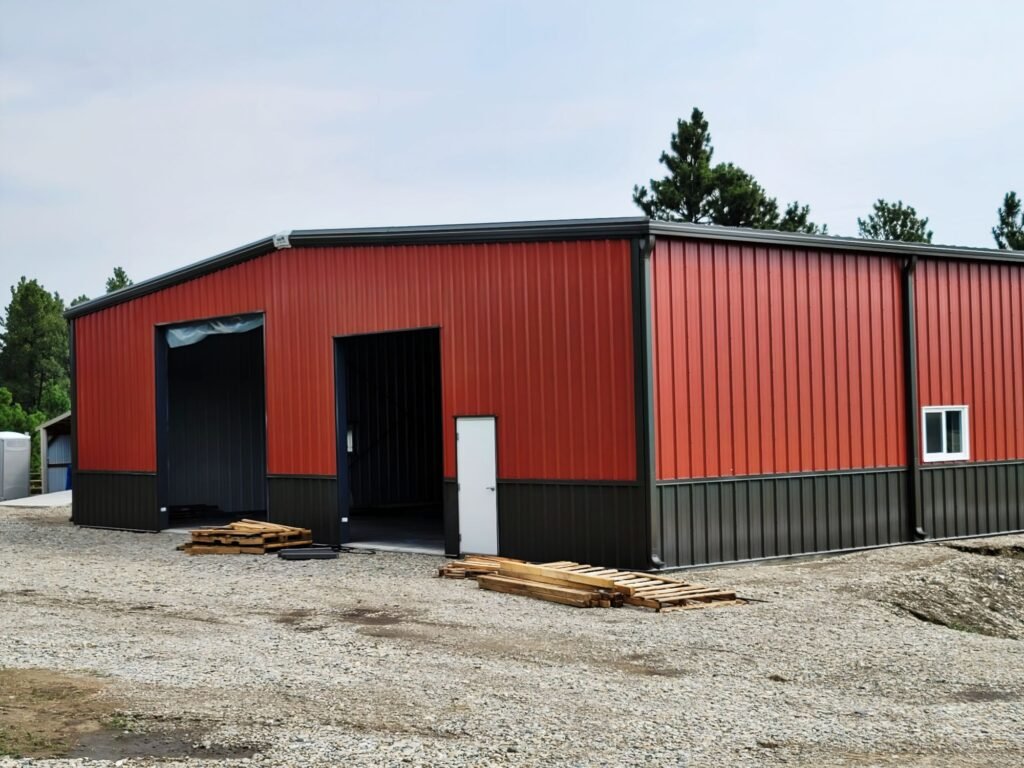 Red and black pre-engineered steel building with framed door and window openings
