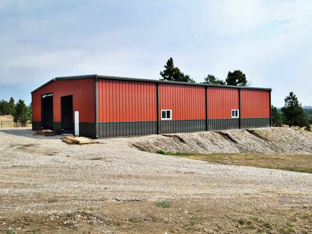 Industrial-grade pre-engineered metal building with red steel siding and framed access doors