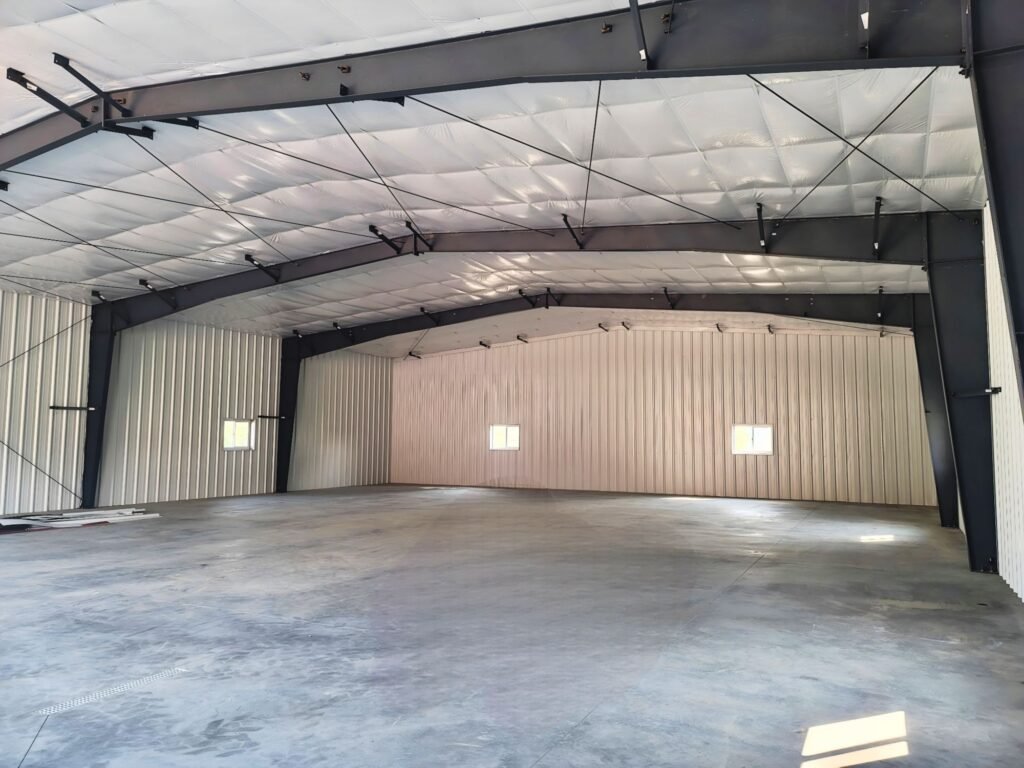Interior of insulated pre-engineered steel building with open-span framing and concrete flooring